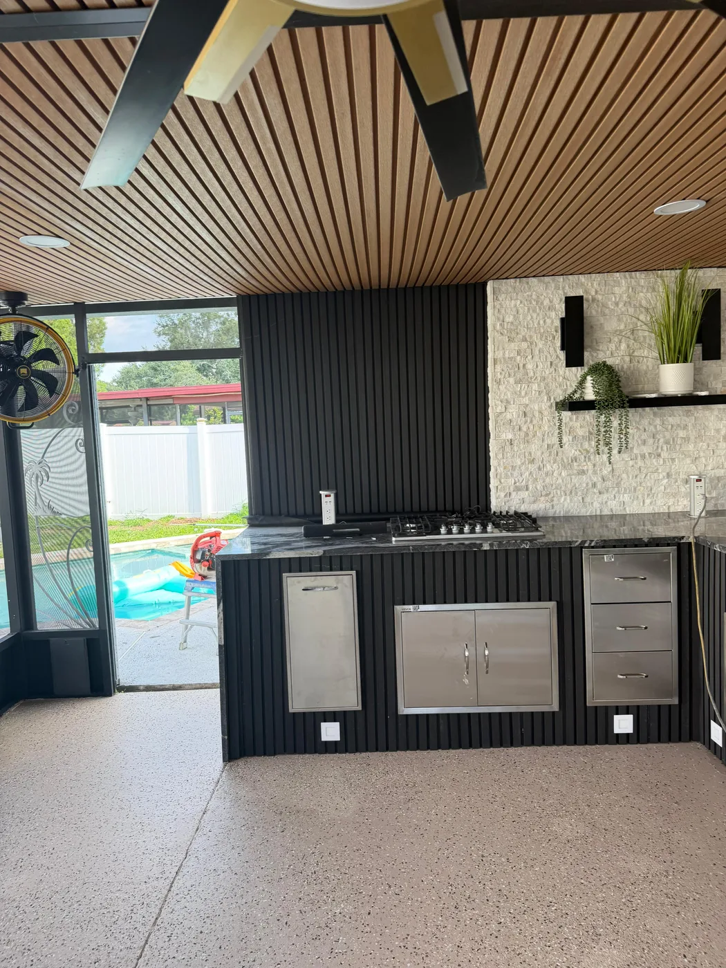Outdoor kitchen under a slat-wood ceiling
